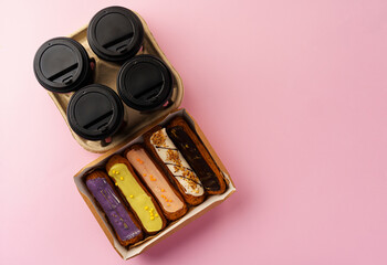 Box of eclairs with takeaway coffee cups on pink background