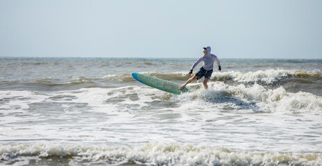 Panoramic view of middle aged man surfing in the Atlantic Ocean.