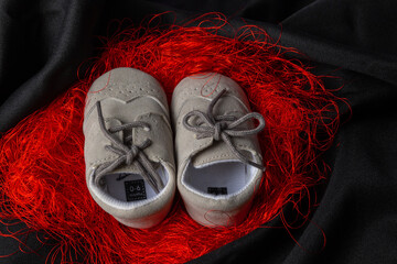 Baby boy shoes with red thread, shower invitation concept on black background, banner, copy space, top view