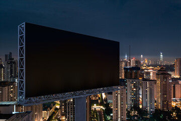 Blank black road billboard with KL cityscape background at night time. Street advertising poster, mock up, 3D rendering. Side view. The concept of marketing communication to promote or sell idea.