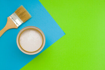 Tools for construction and decoration. A paintbrush and a metal can of paint. Bright background, top view.