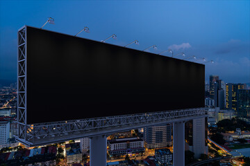 Blank black road billboard with KL cityscape background at night time. Street advertising poster, mock up, 3D rendering. Side view. The concept of marketing communication to promote or sell idea.