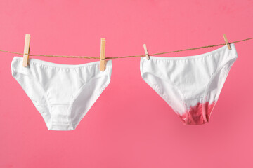 Woman's underwear on clothesline isolated on pink background, concept poster about women's health and menstruation