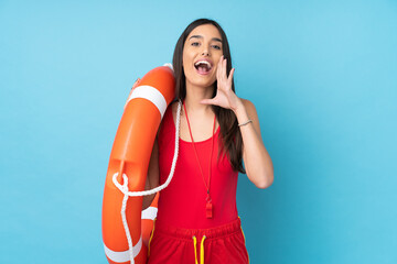 Lifeguard woman over isolated blue background with lifeguard equipment and shouting with mouth wide...
