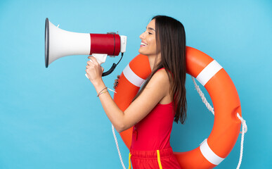 Lifeguard woman over isolated blue background with lifeguard equipment and shouting through a...