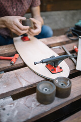 Close-up view of male hands holding skateboard wheel. Man's hands assembling skateboard while placing wheels to truck.