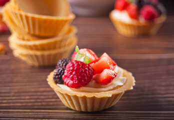 Delicious mini tart tartlets with fresh berries on wooden background