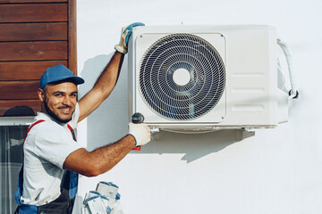Repairman in uniform installing the outside unit of air conditioner