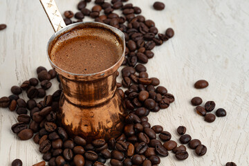 Close up of copper coffee turk on light textured surface