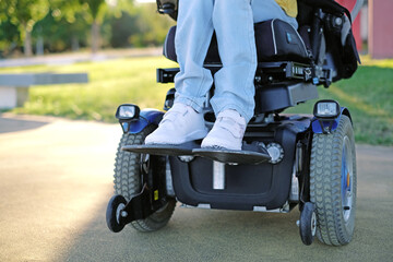 A disabled woman sitting in a blue electric wheelchair outdoors