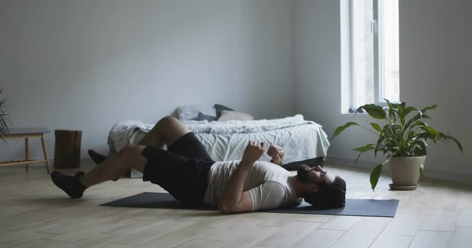 Young man lying on floor, stretching his legs