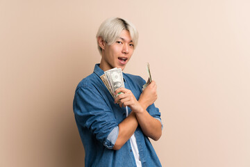 Young asian man over isolated background taking a lot of money