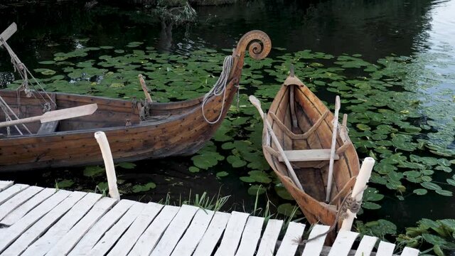 This stock video shows vintage Viking style wooden boats moored on the edge of a lake.