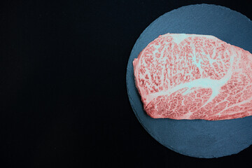 黒い皿に乗った新鮮なステーキ肉