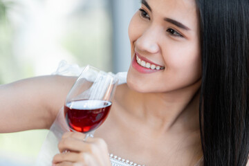 Selfie using a smartphone of Happy of smiling Asian young female sitting at a table food holding with wine glasses at in the restaurant background