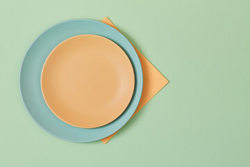 Table setting. Celebration concept. Holiday event. Top view of empty plates and napkin isolated on green, copy space