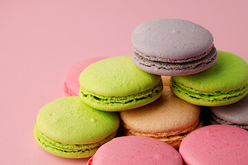 Fototapeta na wymiar Pile of colorful macaroon cookies on pink background