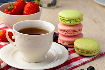 Cup of coffee with colorful cookies close up