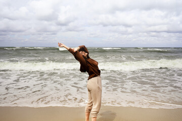 man running on the beach spending leisure time, walking around the beach, watching tide and waves at a Baltic Sea, smiling young woman