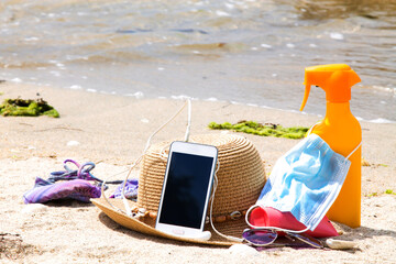 mobile phone, suntan lotion, medical mask and sunglasses, summer vacation concept in the new normal