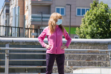 Obraz premium woman with medical mask doing sport exercises on the grass, new normal concept