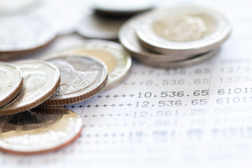 Selective focus of Thai's coins stacked over page of Bank account statement on  white background, Collecting money for investment concept with copy space