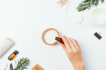 Female hand adds essential oil to sea bath salt