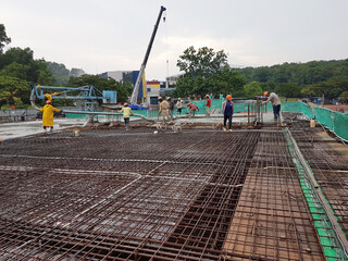KUALA LUMPUR, MALAYSIA -MARCH 3, 2020: Building floor slab under construction. Construction workers fabricating the timber formwork and installing the steel reinforcement bar. 
