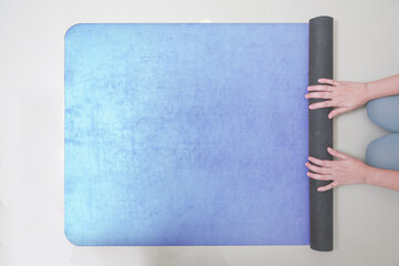 Hands of Woman rolling her Yoga mat after a workout. top view, copy space