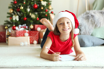 Little girl in Christmas interior writes a letter to Santa Claus
