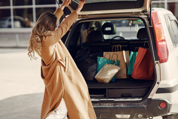 Girl on a shopping. Woman with a shopping bags. Lady near trunk of the car.