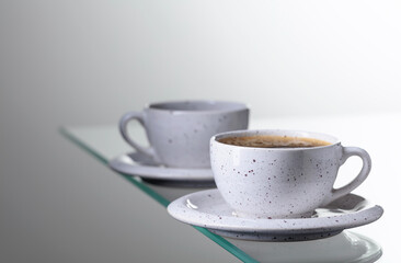 Espresso coffee in ceramic cup on a glass table.