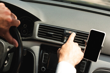 Cropped view of man turning on warning sign near smartphone while driving car