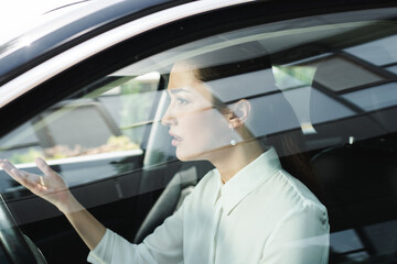 Selective focus of confused businesswoman pointing with hand while driving car