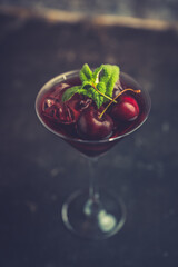 Cherry cocktail in martini glass with berries and mint leaves. Selective focus. Shallow depth of field.