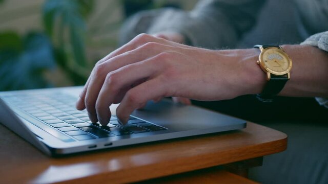 Closeup with energetic movement: man typing on the laptop keyboard, sitting on the couch of his apartment living room, Concept of entrepreneur startup, home worker student or independent businessman