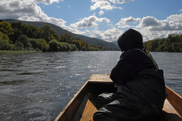 A fisherman (man) sits in a boat and looks at the river. Bolshaya Ussurka river, Primorsky Krai (Primorye), Far East, Russia.