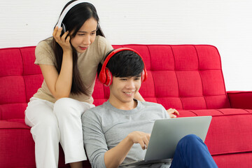 Asian woman and man listening music from their laptops relaxation and enjoyment in the house.