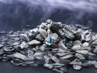 Classy blue drop necklace close-up on top of grey stones