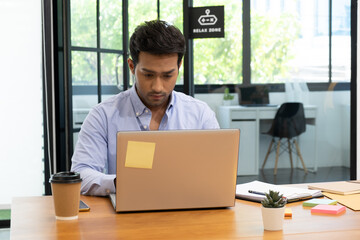 An Asian teenage man is sitting on a desk with a notebook. He is a company manager. he works hard...