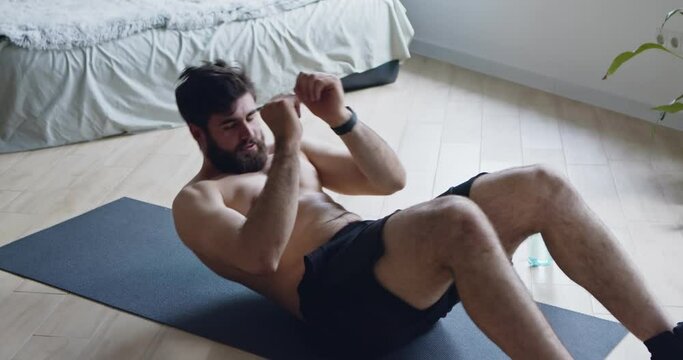 Sporty man doing abs exercises on floor at home