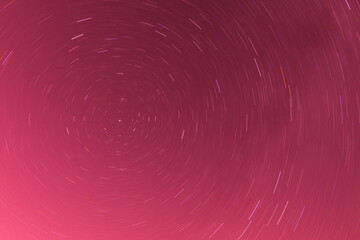 Background of round or circular star track or trajectory on the red, pink or rose clear night sky....