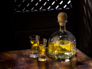 Close up view of bottle of tequila anejo and glasses on color background