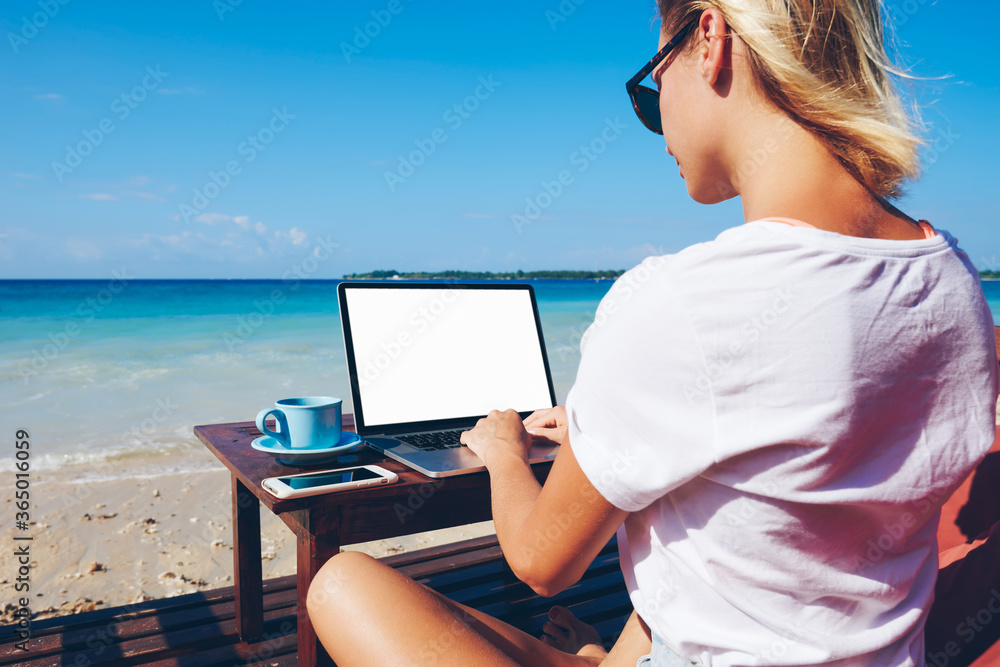 Aufkleber back view of creative female travel blogger networking via netbook with blank screen sitting on ocea