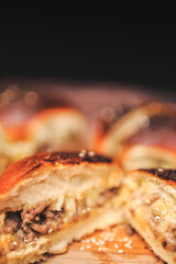Homemade beef burger with cheese sliced in half with other burgers on the side on a wooden board with free space for text/decoration. Interior view of the burger.