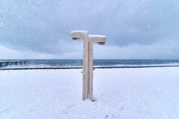 Beach shower in the snow against the background of the dramatic sea in winter