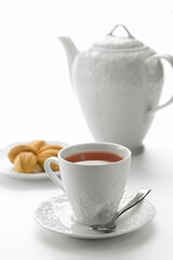 Close up view of dessert plate, china teapot and cups on white background