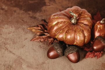 Rustic pumpkin and acorns on brown fall season texture background.