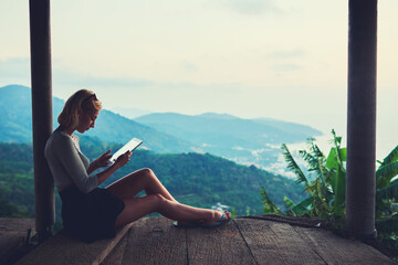 Fototapeta premium Young female freelancer is working in network via touch pad, while is sitting against beautiful view background with copy space for your advertising text message during her unforgettable trip in Asia