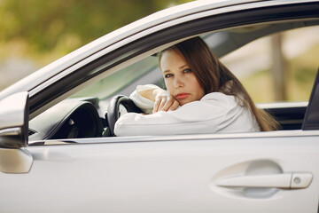 Woman sitting in a car. Lady in a white suit.